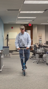 Jamie Eldredge riding a scooter in the office.
